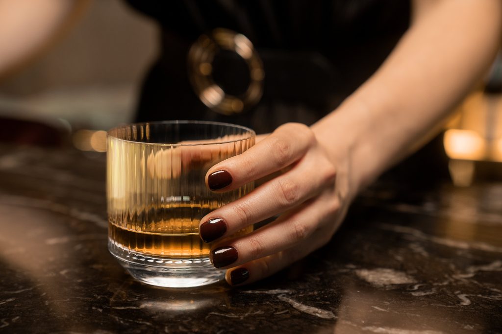 Female hand holding tumbler or whiskey