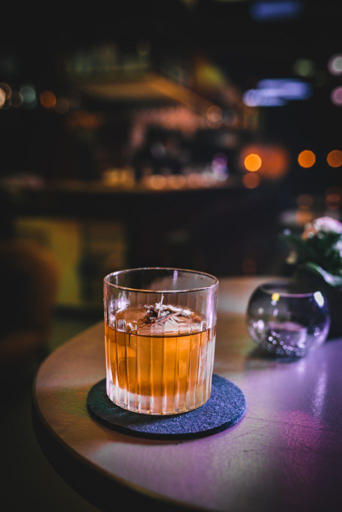 Photo by Jakub Dzuibak depicting a glass of whiskey on a table.